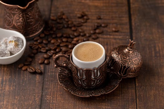 Turkish coffee in classic coffee cup with water and Turkish delight on wooden table