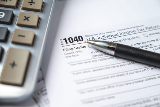 Financial time tax return forms with pen and calculator