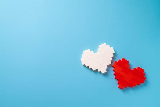 Red and white heart made of plastic bricks on a blue background