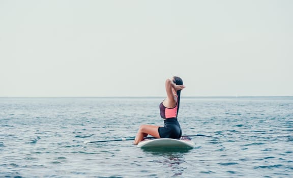 Silhouette of woman standing, surfing on SUP board, confident paddling through water surface. Idyllic sunset or sunrise. Sports active lifestyle at sea or river.