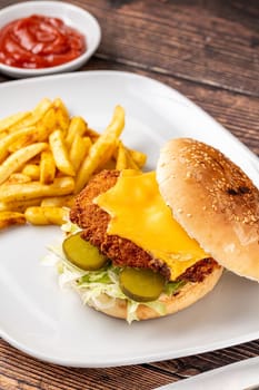 Chicken burger with french fries and ketchup on wooden table