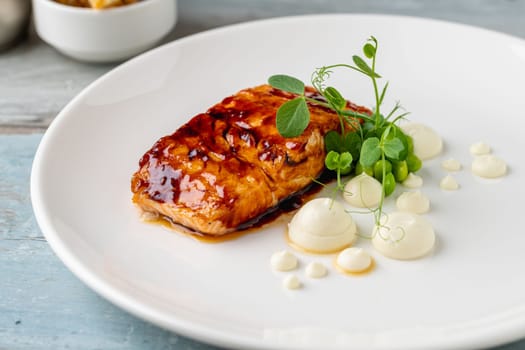 Grilled salmon fillet with sauces next to it on a white porcelain plate