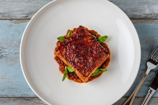 Bechamel sauce and minced meat lasagna on wooden table