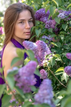 portrait of young woman with long hair outdoors in blooming lilac garden.