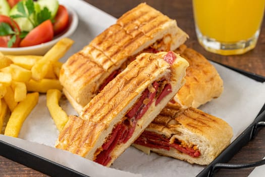 Toast with cheddar cheese and turkish sausage with french fries and salad on wooden table