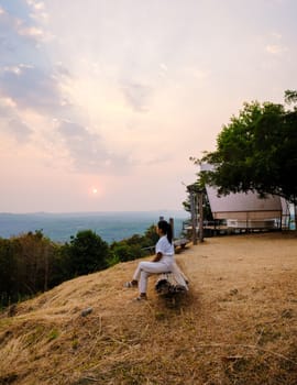 Sunset at a mountain camping in Phitsanulok Thailand. luxury glamping, Thai women watching sunset in the mountains of Northern Thailand