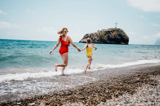 Happy loving family mother and daughter having fun together on the beach. Mum playing with her kid in holiday vacation next to the ocean - Family lifestyle and love concept.