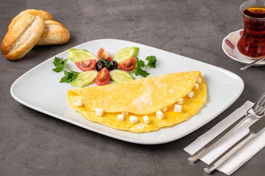 Feta cheese omelet with olives and tomatoes on a white porcelain plate