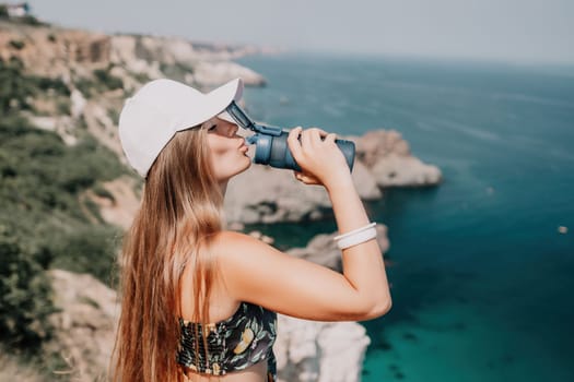 Woman travel sea. Happy tourist taking picture outdoors for memories. Woman traveler looks at the edge of the cliff on the sea bay of mountains, sharing travel adventure journey.