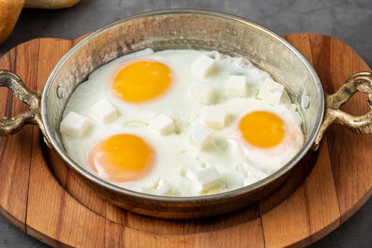 Sunny Side Up Eggs with feta cheese in a copper pan