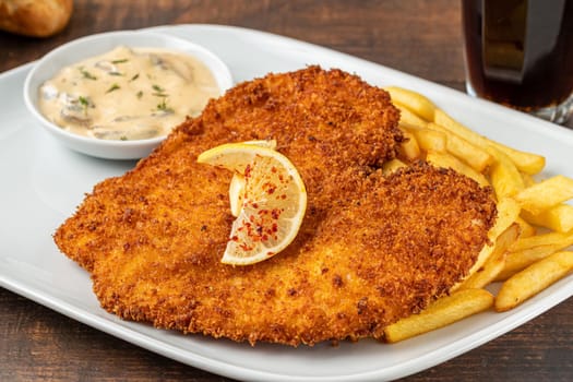 Chicken schnitzel with butter and potato salad on white porcelain plate