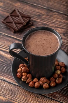 Hazelnut hot chocolate with chocolate next to it on wooden table