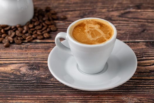 Espresso in white cup with milk next to it on wooden table