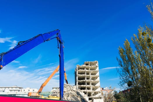 Demolition of a old building with sloopkraan against blue clouds sky.