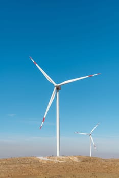 Multiple wind turbines standing on a hill at sunrise and generating electricity