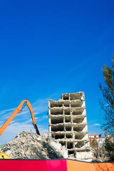 Background of process of demolition of a building. Excavator breaking old house.