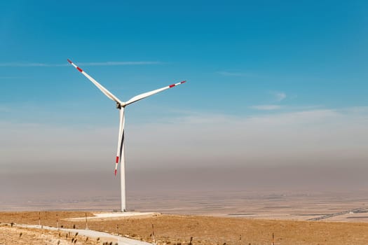 Wind turbine standing on a hill and generating electricity at sunrise