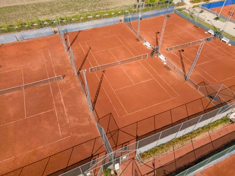 Aerial view of empty clay tennis court on a sunny day