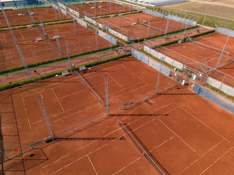 Aerial view of empty clay tennis court on a sunny day