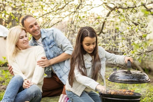 Happy family having a barbecue in their garden in spring. Leisure, food, family and holidays concept