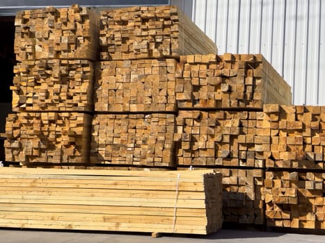 Timbers stacked on top of each other in front of the warehouse. Wooden beam