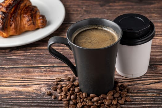 Relaxing americano coffee in black porcelain cup and take away cup on wooden table