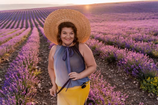 Woman lavender field sunset. Romantic woman walks through the lavender fields. illuminated by sunset sunlight. Dressed in a dress with a hat