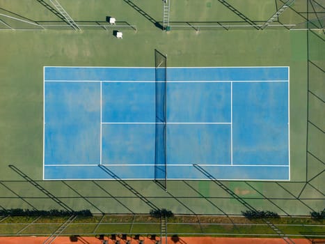 Aerial view of empty blue hard tennis court on a sunny day