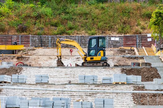 Small stopped excavator with a shovel at the construction site