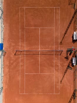 Aerial view of empty clay tennis court on a sunny day