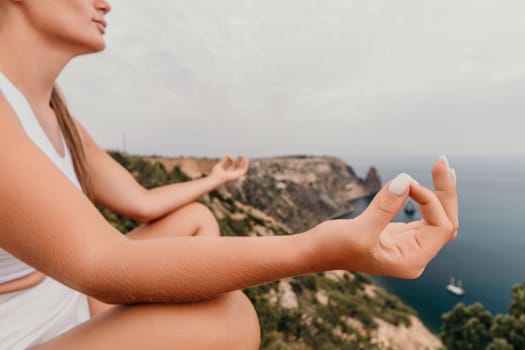 Middle aged well looking woman with black hair doing Pilates with the ring on the yoga mat near the sea on the pebble beach. Female fitness yoga concept. Healthy lifestyle, harmony and meditation.