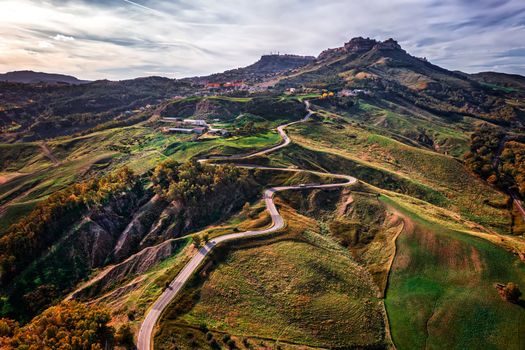 Aerial photo of a curved mountain road under the mountain peak.