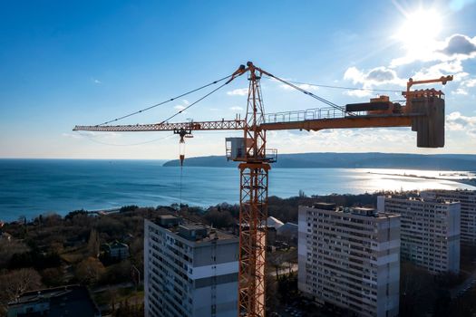 View from a drone to construction tower crane against a blue sky
