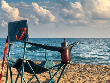 Folding camping chair facing the sea on the beach in the evening in autumn