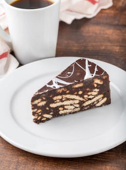 Chocolate mosaic cake on a white porcelain plate with filter coffee on the side