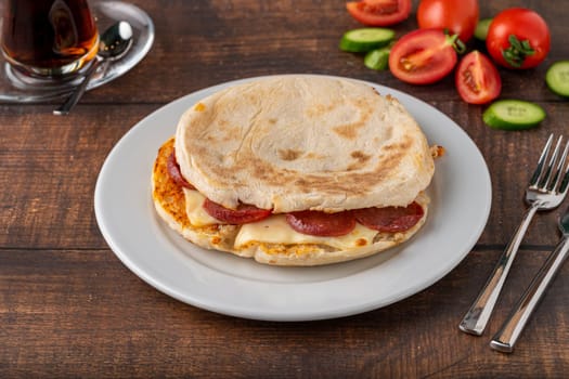 Flatbread toast with salami, turkish sausage and cheddar on a dark stone table