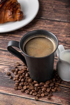 Relaxing americano coffee in black porcelain cup on wooden table