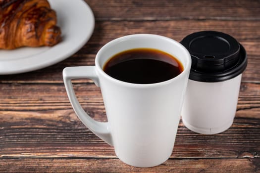 Relaxing filter coffee in white porcelain cup and take away cup on wooden table