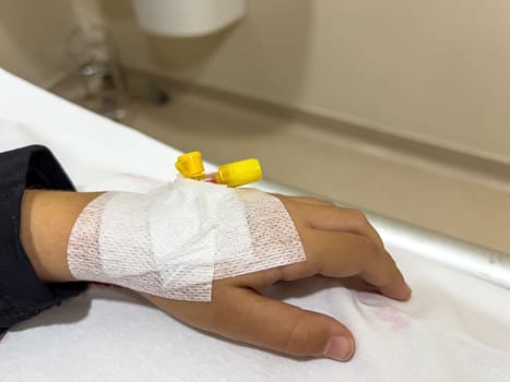 Vascular access on the hand of young sick girl at the hospital bed