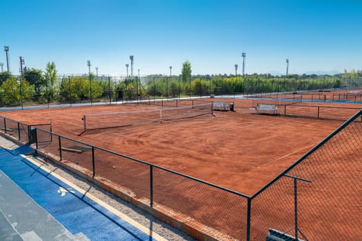 Aerial view of empty clay tennis court on a sunny day