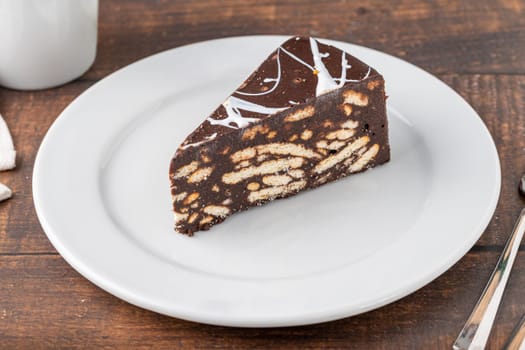 Chocolate mosaic cake on a white porcelain plate with filter coffee on the side