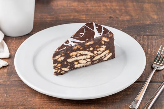 Chocolate mosaic cake on a white porcelain plate with filter coffee on the side