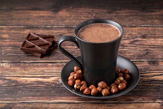 Hazelnut hot chocolate with chocolate next to it on wooden table