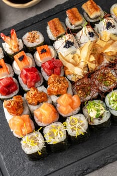 Sushi set of various products on a black stone plate. Blur background and selective focus