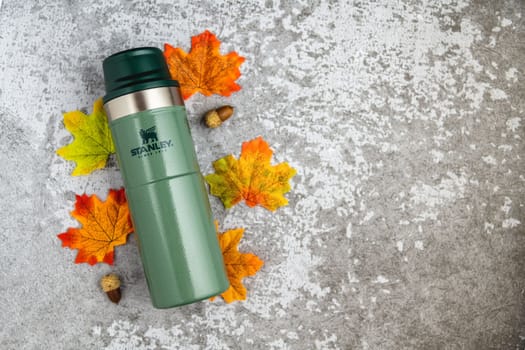 Antalya, Turkey - November 28, 2022: Stanley Action Trigger thermos mug with leaves in autumn colors on stone background