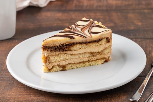 A slice of white chocolate and caramel cake on wooden table