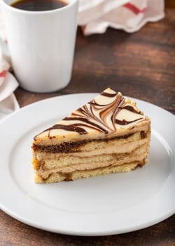 A slice of white chocolate and caramel cake on wooden table