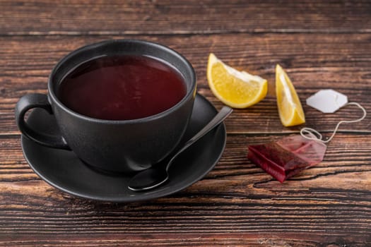 Packed brewed winter tea in black porcelain cup on wooden table