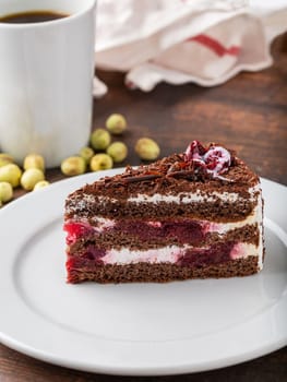 Cherry cake on white porcelain plate on wooden table