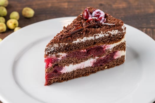 Cherry cake on white porcelain plate on wooden table